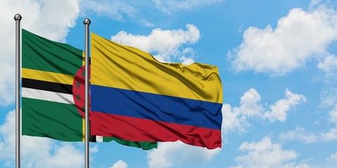Dominica and Colombia flag waving in the wind against white cloudy blue sky together. Diplomacy...