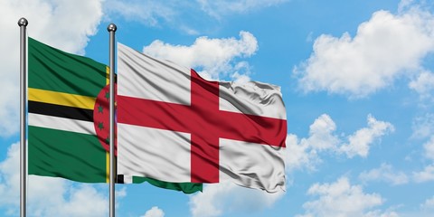 Dominica and England flag waving in the wind against white cloudy blue sky together. Diplomacy...