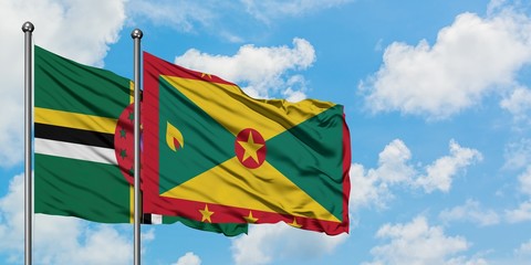 Dominica and Grenada flag waving in the wind against white cloudy blue sky together. Diplomacy concept, international relations.