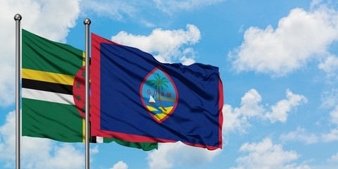 Dominica and Guam flag waving in the wind against white cloudy blue sky together. Diplomacy...