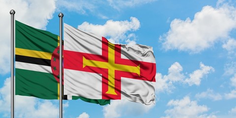 Dominica and Guernsey flag waving in the wind against white cloudy blue sky together. Diplomacy concept, international relations.