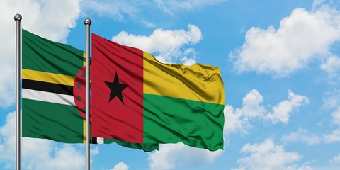Dominica and Guinea Bissau flag waving in the wind against white cloudy blue sky together. Diplomacy concept, international relations.
