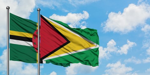 Dominica and Guyana flag waving in the wind against white cloudy blue sky together. Diplomacy concept, international relations.