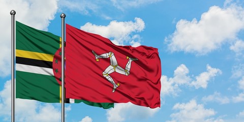 Dominica and Isle Of Man flag waving in the wind against white cloudy blue sky together. Diplomacy...