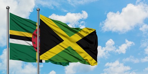 Dominica and Jamaica flag waving in the wind against white cloudy blue sky together. Diplomacy concept, international relations.