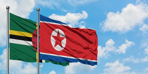 Dominica and North Korea flag waving in the wind against white cloudy blue sky together. Diplomacy concept, international relations.