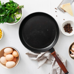 Healthy breakfast table with empty cooking pan with ingredient for cooking. Eggs, broccoli, corn, spinach, parsley, mushrooms and cheese on white wooden background top view