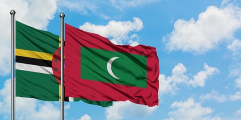 Dominica and Maldives flag waving in the wind against white cloudy blue sky together. Diplomacy...