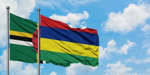 Dominica and Mauritius flag waving in the wind against white cloudy blue sky together. Diplomacy concept, international relations.