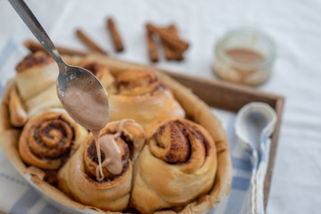 Cinnamon rolls with sugar frosting. With cinnamon sticks and spices, wooden background
