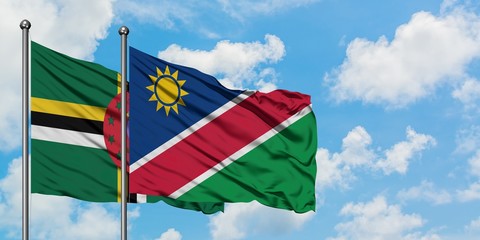 Dominica and Namibia flag waving in the wind against white cloudy blue sky together. Diplomacy...