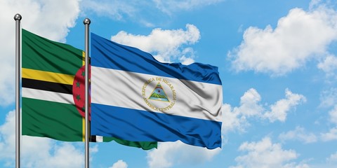 Dominica and Nicaragua flag waving in the wind against white cloudy blue sky together. Diplomacy concept, international relations.