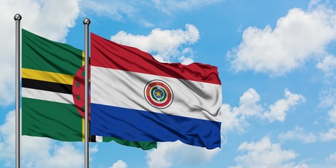 Dominica and Paraguay flag waving in the wind against white cloudy blue sky together. Diplomacy...