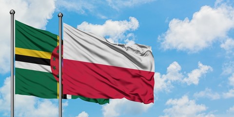 Dominica and Poland flag waving in the wind against white cloudy blue sky together. Diplomacy...
