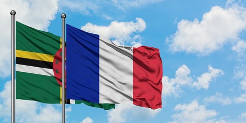 Dominica and Reunion flag waving in the wind against white cloudy blue sky together. Diplomacy concept, international relations.