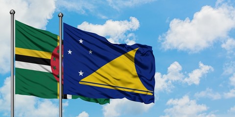 Dominica and Tokelau flag waving in the wind against white cloudy blue sky together. Diplomacy...