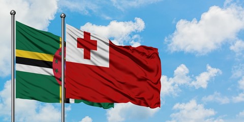 Dominica and Tonga flag waving in the wind against white cloudy blue sky together. Diplomacy...