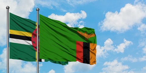 Dominica and Zambia flag waving in the wind against white cloudy blue sky together. Diplomacy...