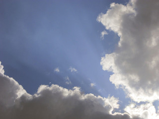 Sunbeams breaking through storm clouds in a blue sky.