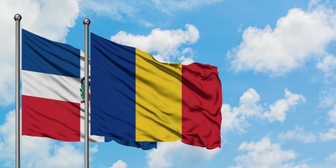Dominican Republic and Romania flag waving in the wind against white cloudy blue sky together. Diplomacy concept, international relations.