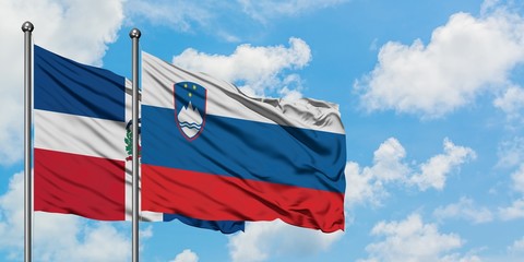 Dominican Republic and Slovenia flag waving in the wind against white cloudy blue sky together. Diplomacy concept, international relations.