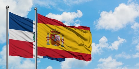 Dominican Republic and Spain flag waving in the wind against white cloudy blue sky together. Diplomacy concept, international relations.