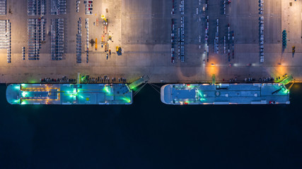 Aerial top view car carrier vessel at night, rows of new cars at night waiting to be dispatch and shipped import export new cars.