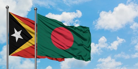 East Timor and Bangladesh flag waving in the wind against white cloudy blue sky together. Diplomacy...