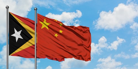 East Timor and China flag waving in the wind against white cloudy blue sky together. Diplomacy concept, international relations.