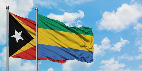 East Timor and Gabon flag waving in the wind against white cloudy blue sky together. Diplomacy concept, international relations.