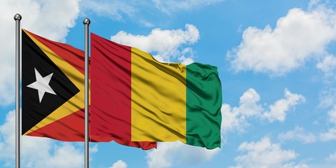East Timor and Guinea flag waving in the wind against white cloudy blue sky together. Diplomacy concept, international relations.