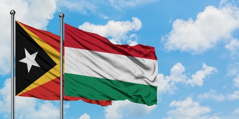 East Timor and Hungary flag waving in the wind against white cloudy blue sky together. Diplomacy concept, international relations.