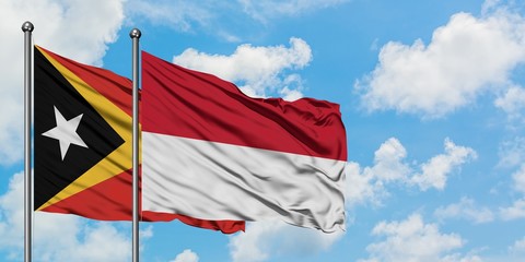 East Timor and Indonesia flag waving in the wind against white cloudy blue sky together. Diplomacy concept, international relations.
