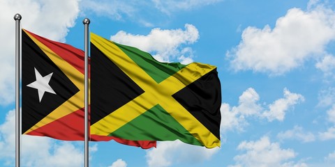 East Timor and Jamaica flag waving in the wind against white cloudy blue sky together. Diplomacy concept, international relations.