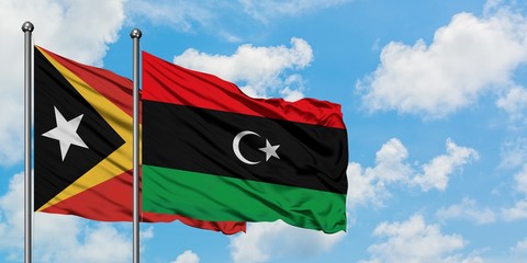 East Timor and Libya flag waving in the wind against white cloudy blue sky together. Diplomacy concept, international relations.