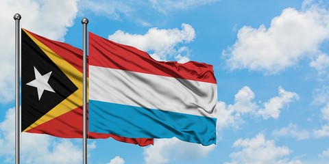East Timor and Luxembourg flag waving in the wind against white cloudy blue sky together. Diplomacy concept, international relations.