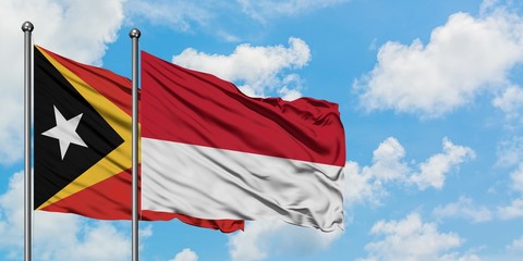 East Timor and Monaco flag waving in the wind against white cloudy blue sky together. Diplomacy concept, international relations.