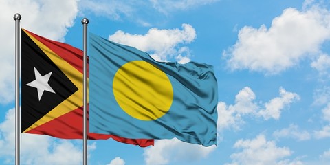 East Timor and Palau flag waving in the wind against white cloudy blue sky together. Diplomacy concept, international relations.