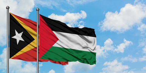 East Timor and Palestine flag waving in the wind against white cloudy blue sky together. Diplomacy concept, international relations.