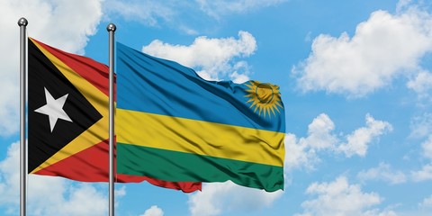 East Timor and Rwanda flag waving in the wind against white cloudy blue sky together. Diplomacy concept, international relations.