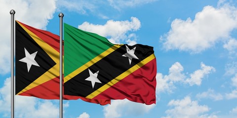 East Timor and Saint Kitts And Nevis flag waving in the wind against white cloudy blue sky together. Diplomacy concept, international relations.