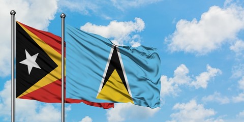 East Timor and Saint Lucia flag waving in the wind against white cloudy blue sky together. Diplomacy concept, international relations.
