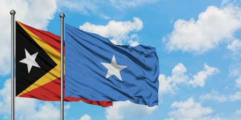 East Timor and Somalia flag waving in the wind against white cloudy blue sky together. Diplomacy concept, international relations.