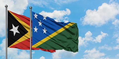 East Timor and Solomon Islands flag waving in the wind against white cloudy blue sky together. Diplomacy concept, international relations.