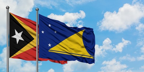 East Timor and Tokelau flag waving in the wind against white cloudy blue sky together. Diplomacy concept, international relations.