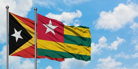 East Timor and Togo flag waving in the wind against white cloudy blue sky together. Diplomacy concept, international relations.