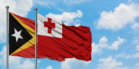 East Timor and Tonga flag waving in the wind against white cloudy blue sky together. Diplomacy concept, international relations.