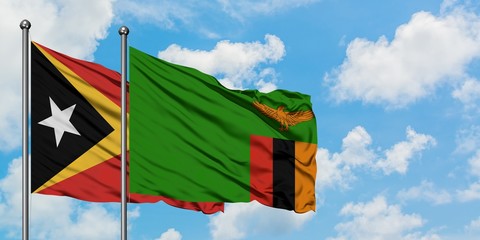 East Timor and Zambia flag waving in the wind against white cloudy blue sky together. Diplomacy concept, international relations.