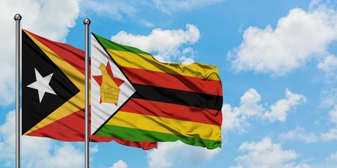 East Timor and Zimbabwe flag waving in the wind against white cloudy blue sky together. Diplomacy concept, international relations.