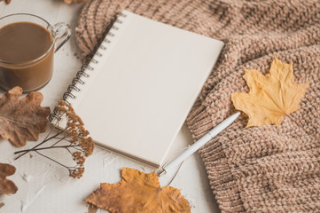 Autumn background with a notebook, pen, a cup of coffee and a sweater. Autumn planning.